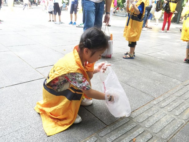 小小志愿者捡起污染公园的垃圾。